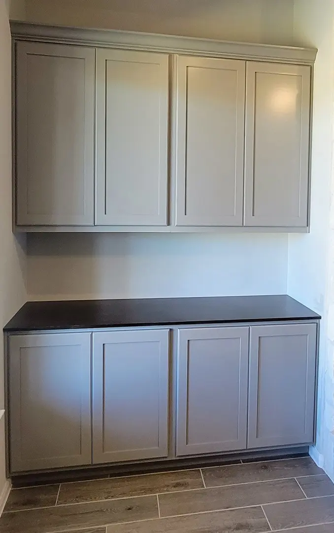 A modern gray built-in cabinet with upper and lower units and a dark countertop offers exceptional custom furnishing.