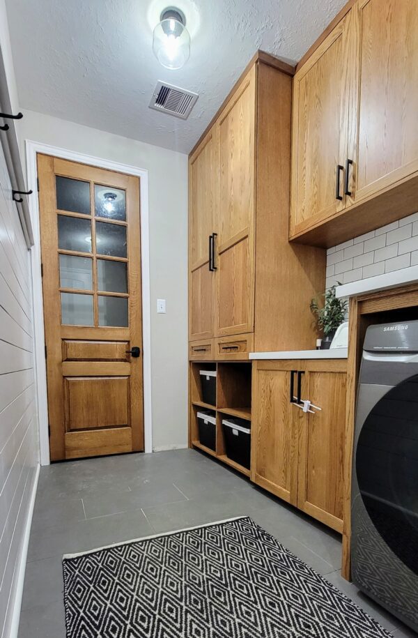 A modern kitchen with exceptional custom wooden cabinets, a geometric-patterned rug on the floor, and a glass-paned door.