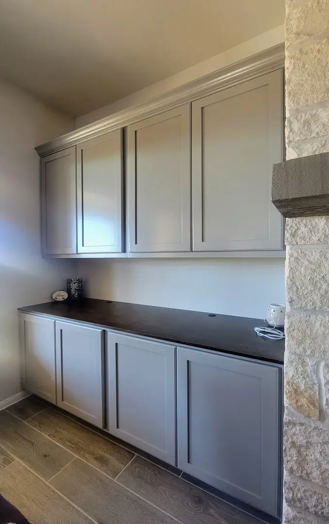 A modern kitchen sideboard with upper and lower cabinets featuring a stone accent wall, elevated by exceptional custom furnishing.