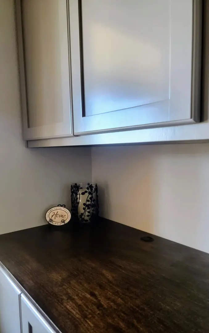 A kitchen countertop with an exceptional decorative plate and a patterned napkin holder under a white cabinet.