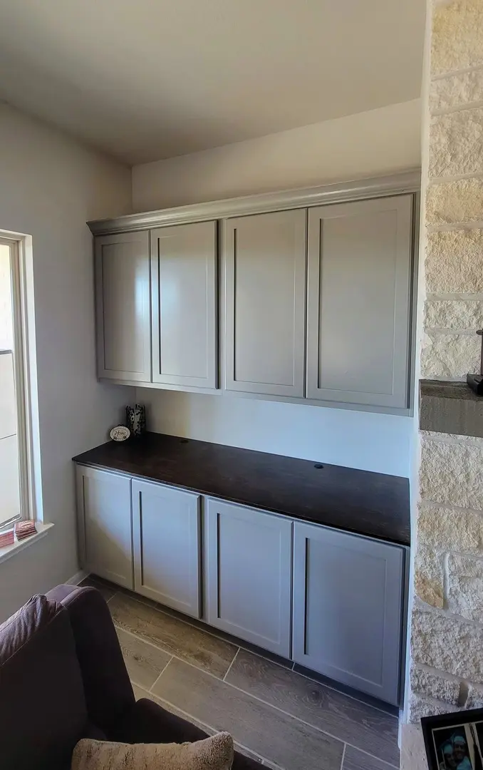 A modern built-in wall storage unit with upper and lower cabinets in a room with stone accent wall features exceptional custom furnishing.