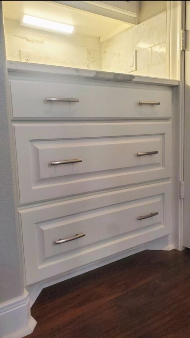 An exceptional custom-built white bathroom vanity with drawers and metallic handles.