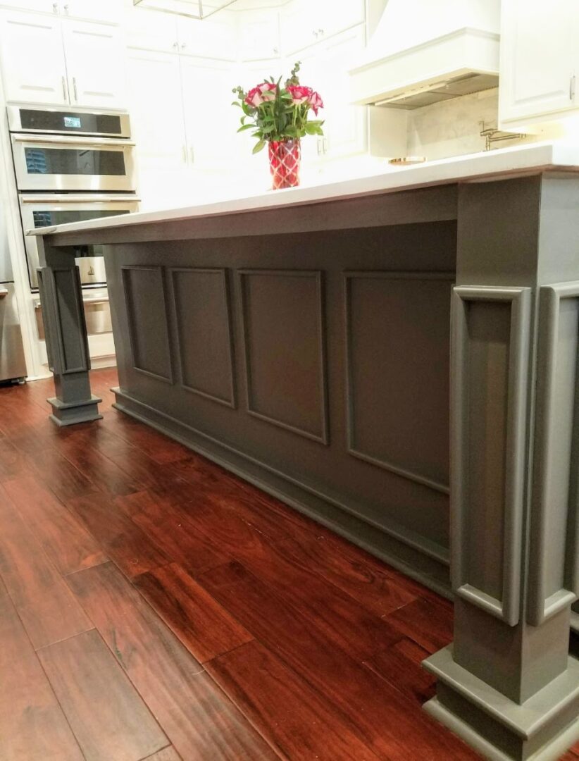 Modern kitchen interior with wooden flooring and an island with gray paneling, enhanced by exceptional custom furnishing.