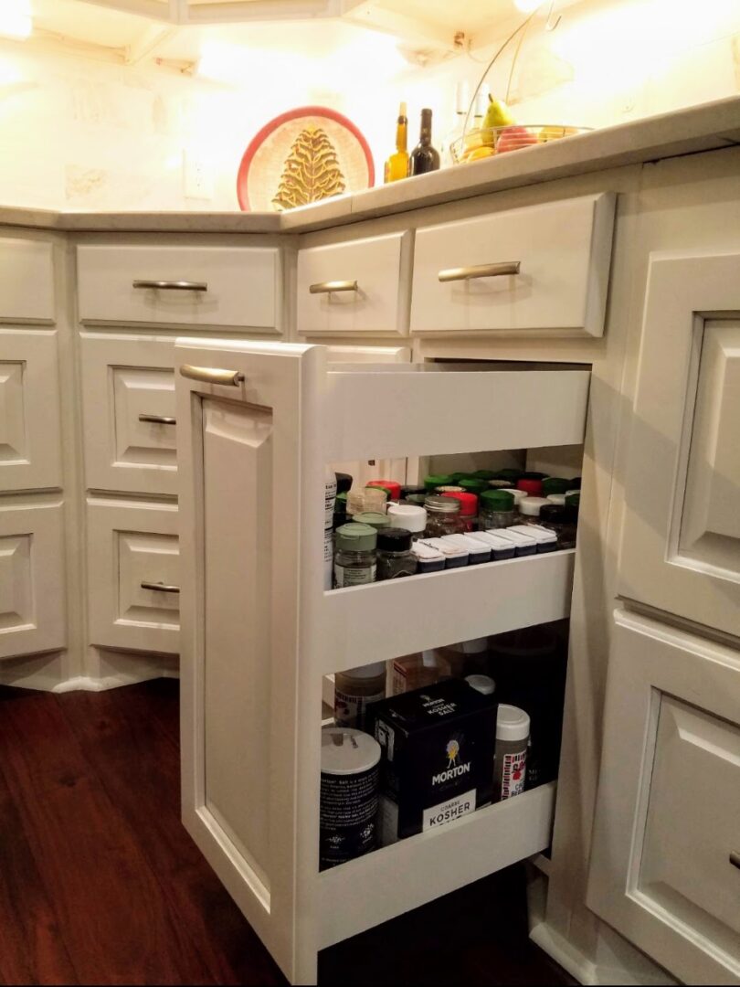 An exceptional corner kitchen cabinet with a pull-out storage solution containing various spices and condiments.