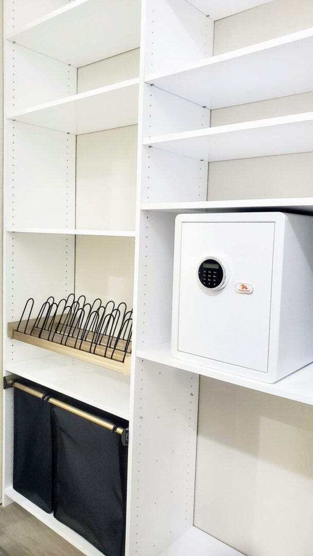 Organized closet with a white safe, shelf dividers, and hanging fabric storage bins featuring exceptional custom furnishing.