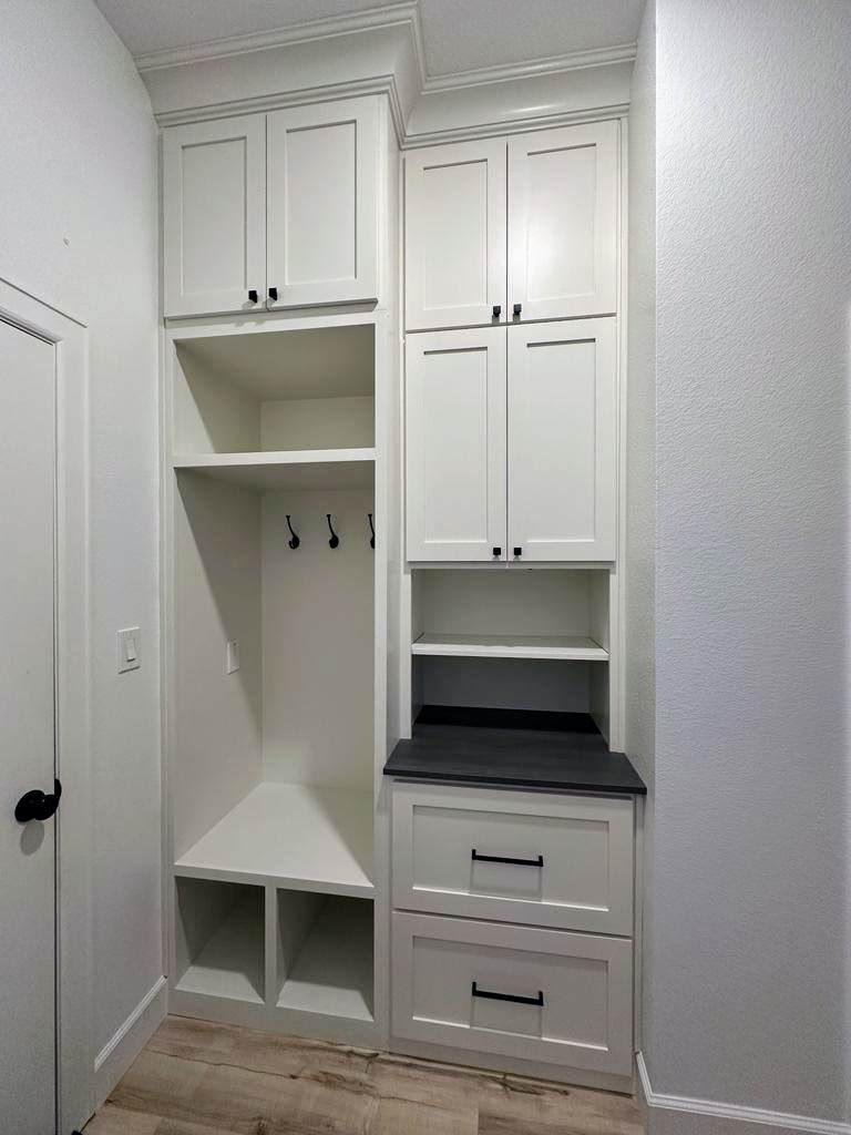 An exceptional custom white built-in hallway storage unit with cabinets, hooks, and drawers.