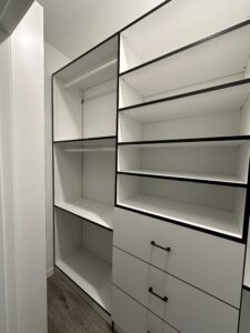 Empty white built-in closet organizer with shelves and drawers, an exceptional custom furnishing.