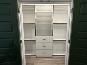 A clean, empty built-in closet with white shelves and drawers, offering exceptional custom furnishing.