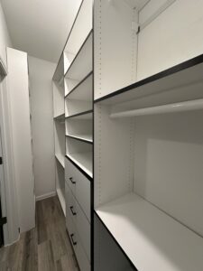 A clean, empty walk-in closet with exceptional custom white shelving and drawers.