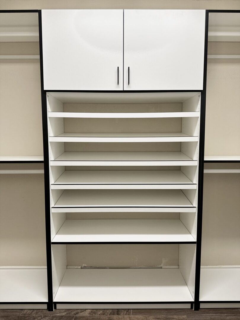 Empty white shelving unit with a closed top cabinet against a beige wall.