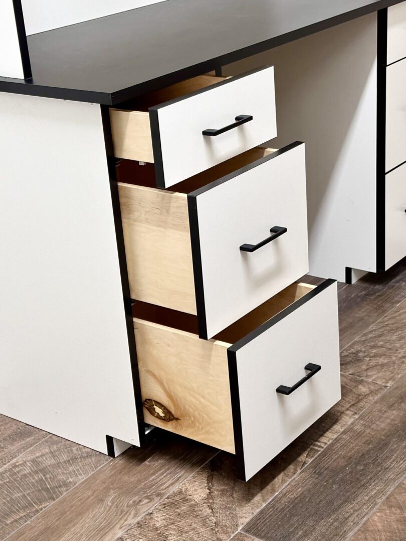 Open white drawers with black handles in a modern kitchen.