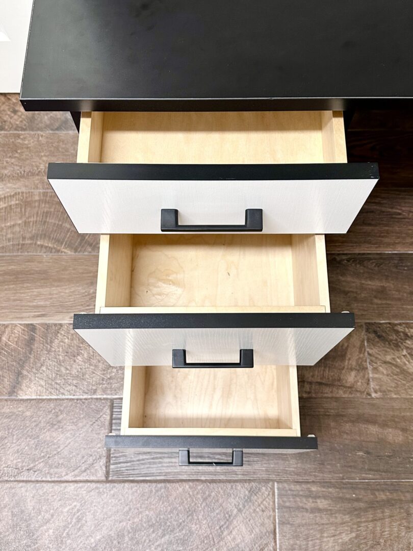 Three open drawers in a wooden desk, viewed from above.