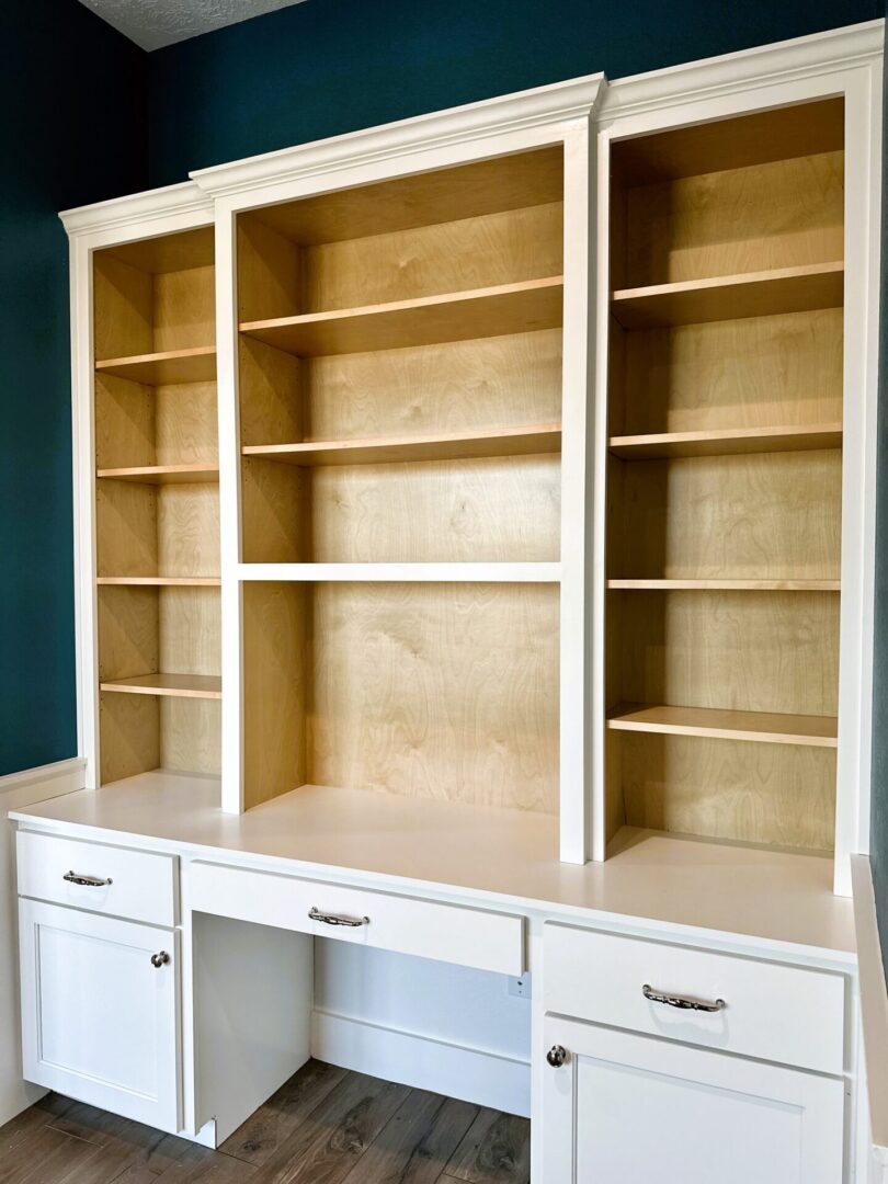 Built-in wooden bookshelves with lower cabinets against a blue wall offer exceptional custom furnishing.