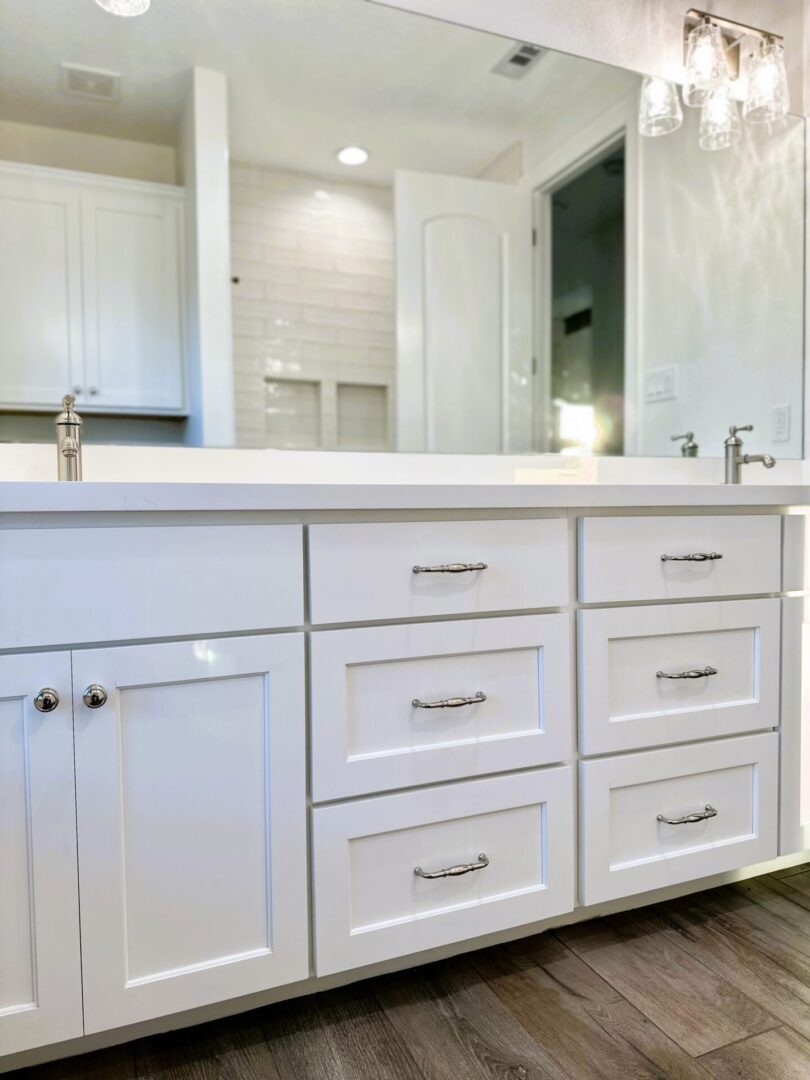 Modern white bathroom vanity with exceptional custom furnishing, cabinets and drawers against a tiled backsplash.