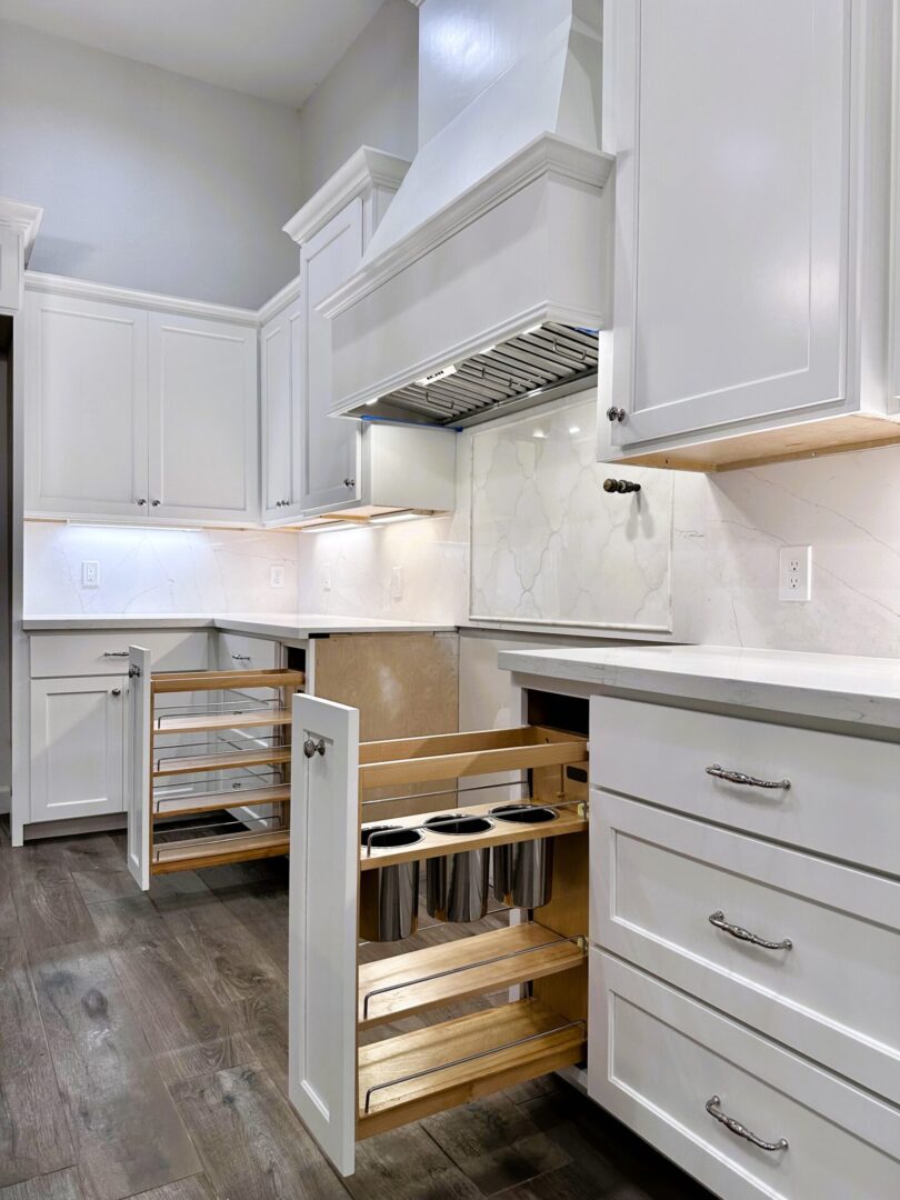 A modern kitchen with white cabinets, stainless steel handles, exceptional custom furnishing, and pull-out storage solutions.