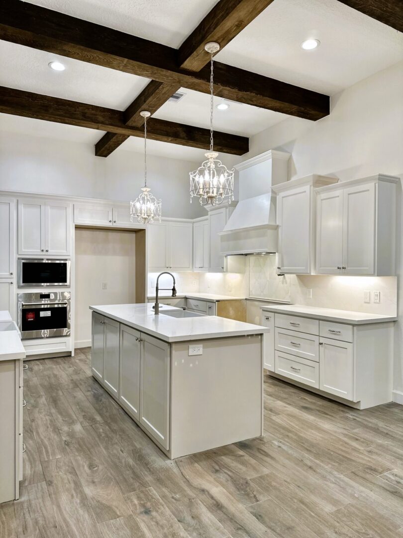 Modern kitchen interior with exceptional custom furnishing, white cabinetry, stainless steel appliances, and wooden ceiling beams.