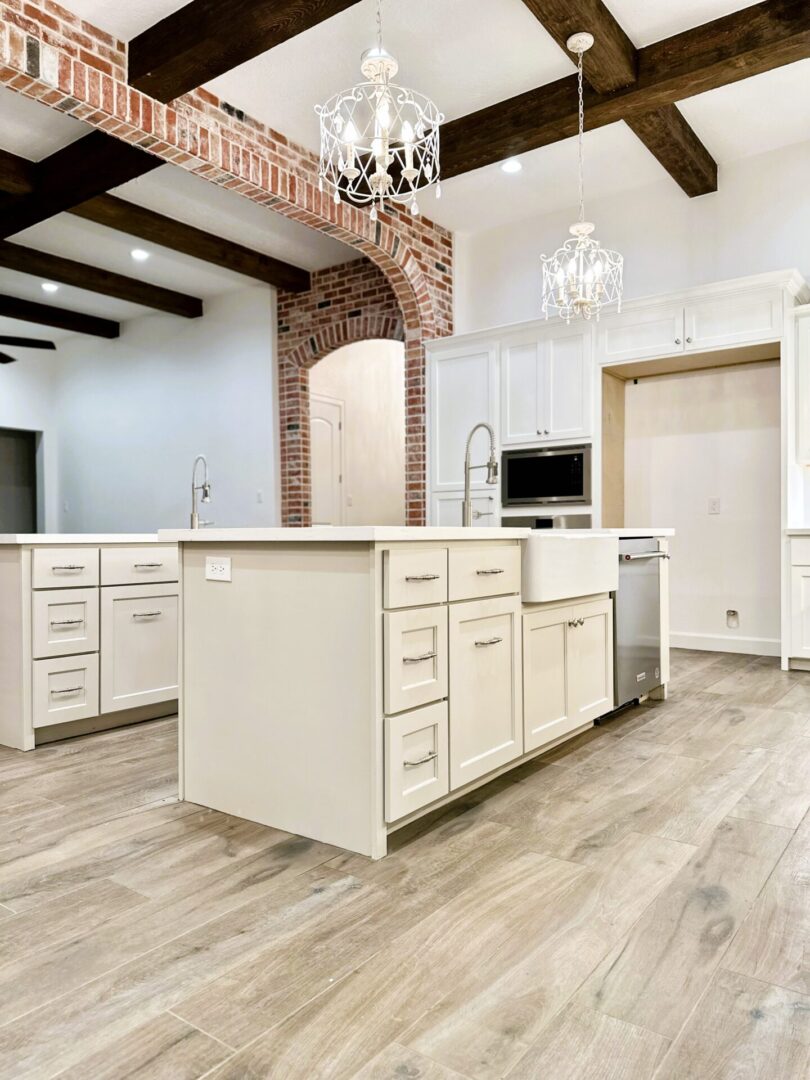 Elegant kitchen interior featuring white cabinets, a brick accent wall, hardwood floors, and exceptional custom furnishing.