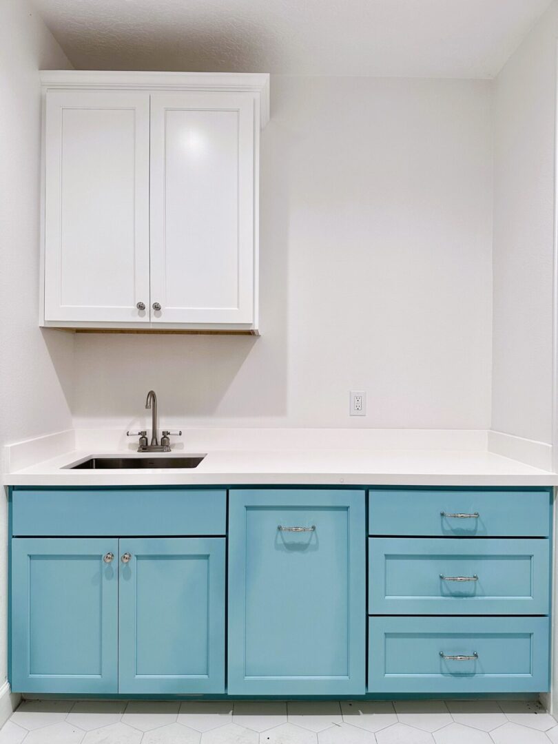 A kitchenette with exceptional custom teal cabinets and a white countertop.