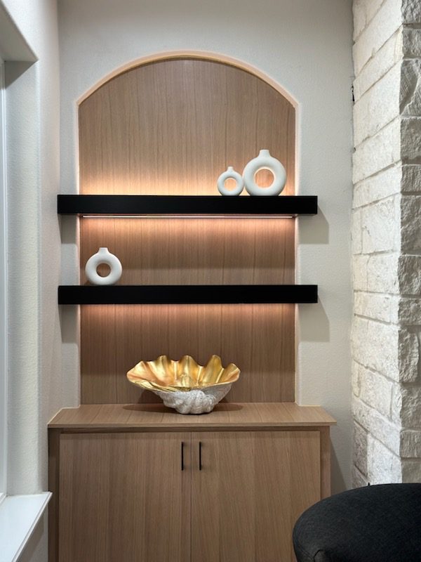 A modern wooden niche with exceptional black shelves, decorative vases, and a golden bowl.