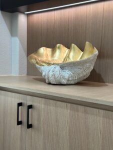 Decorative bowl with a gold interior and textured exterior displayed on an exceptional wooden shelf.