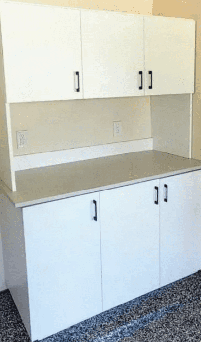 White laminate cabinet with upper and lower storage sections against a plain wall, an example of exceptional custom furnishing.