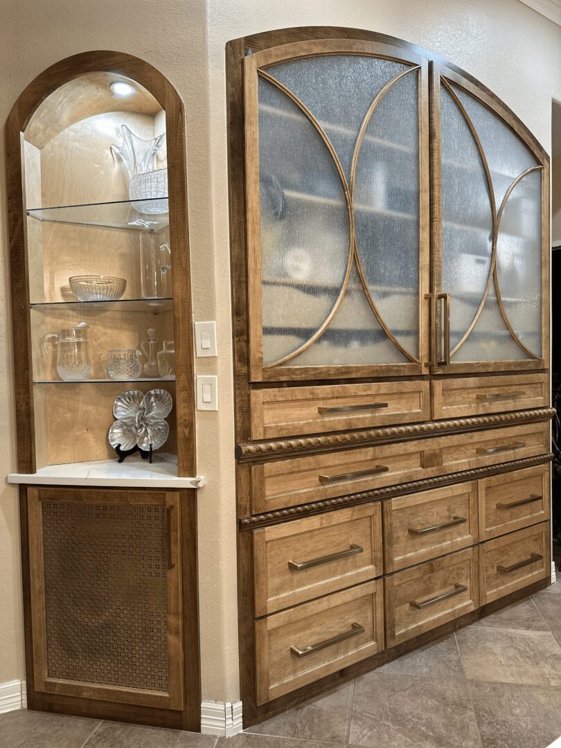 Wooden cabinet with glass doors and drawers displaying dishes and decorative items.