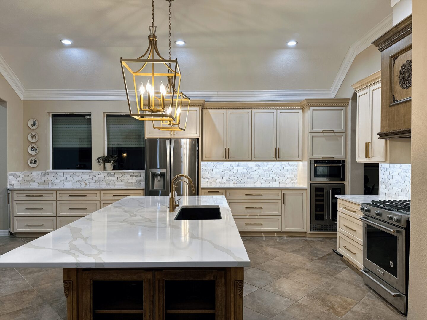 Modern kitchen interior with large island, stainless steel appliances, and pendant lighting.