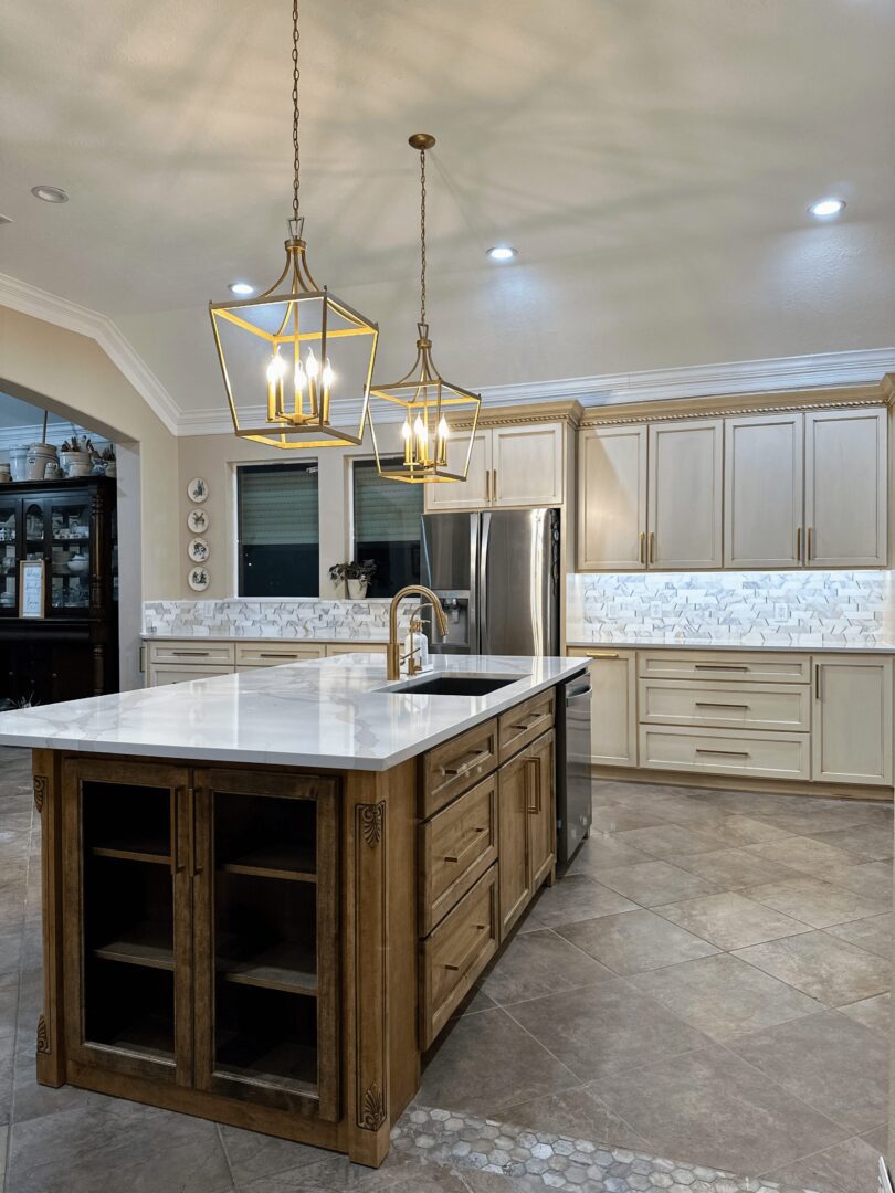 Modern kitchen interior with pendant lights, a central island, stainless steel appliances, and white cabinetry.