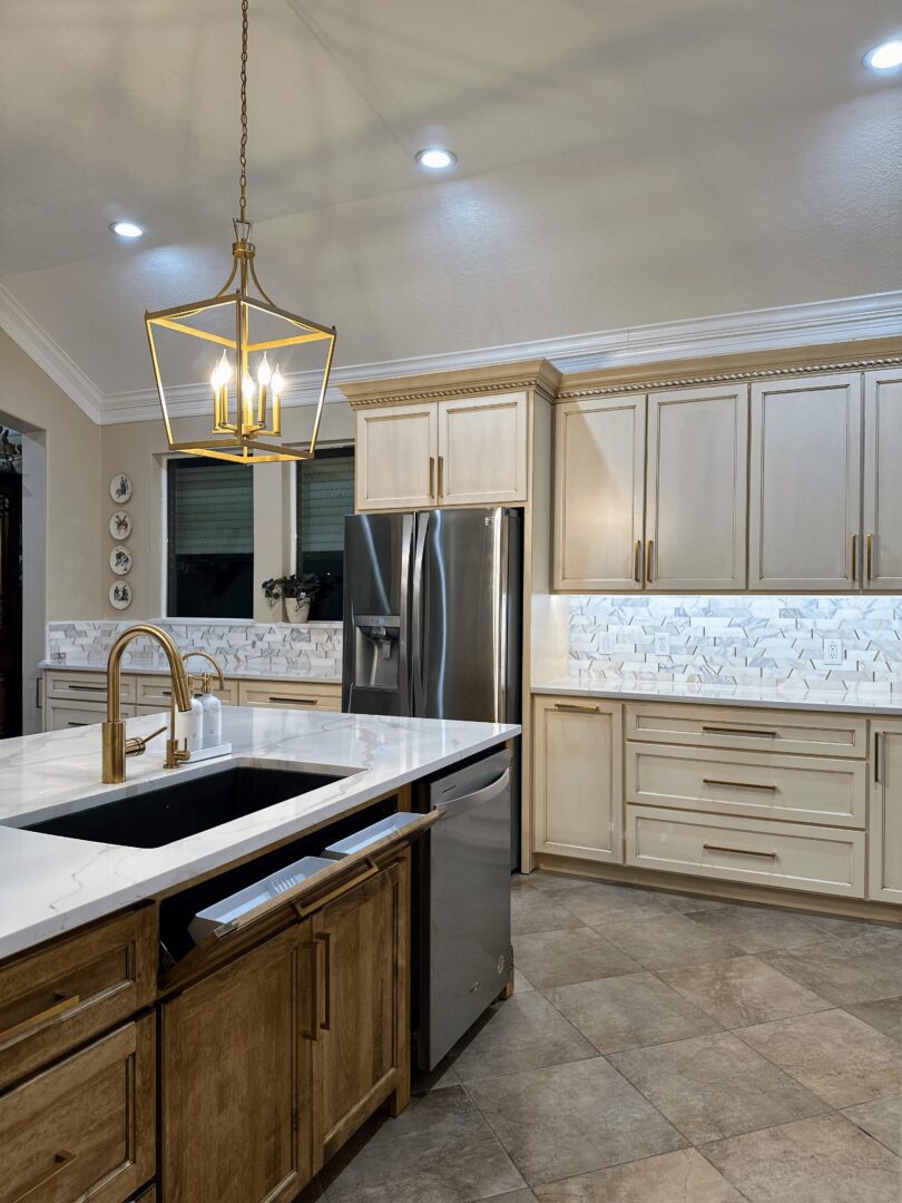 A modern kitchen with stainless steel appliances, white cabinetry, and a central island under pendant lighting.