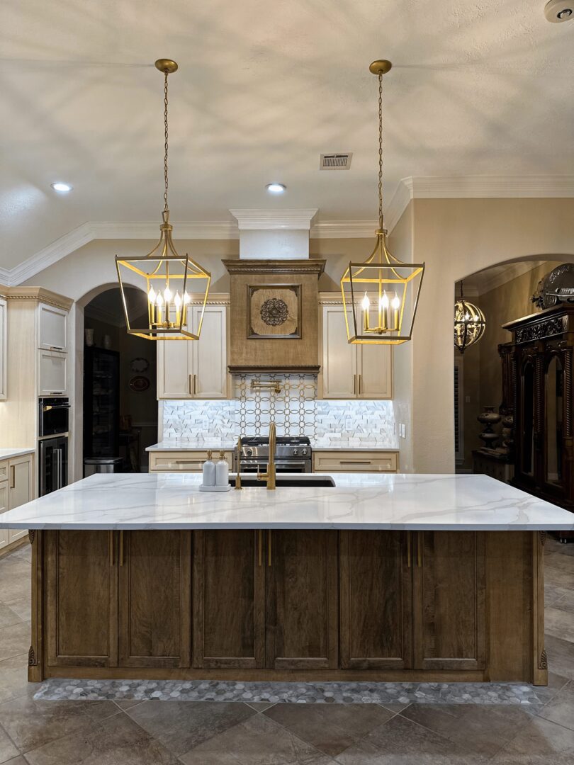 A modern kitchen with a large center island, elegant hanging light fixtures, and white countertops.