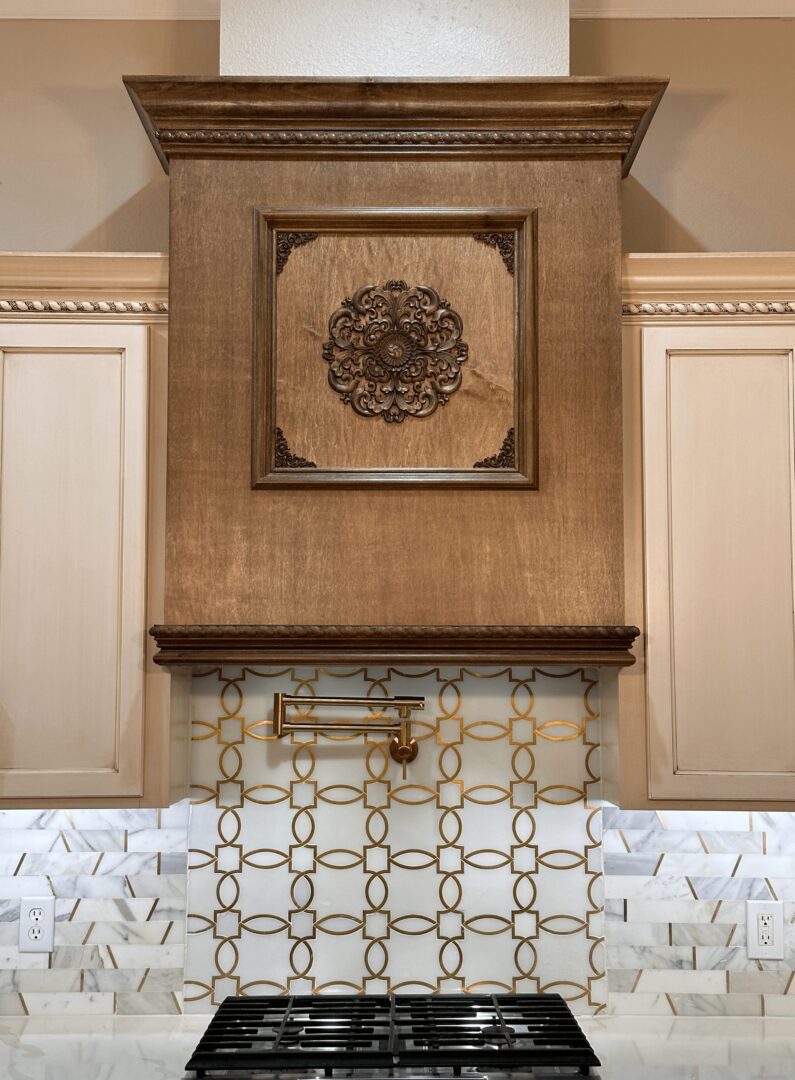 Elegant kitchen stove area with a decorative wooden hood, patterned backsplash, and sleek cooktop.