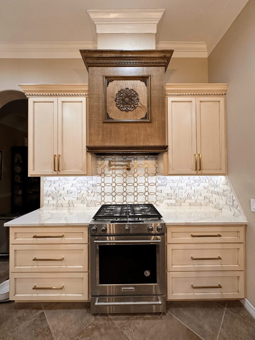 A modern kitchen with beige cabinets, stainless steel stove, and a decorative tile backsplash.