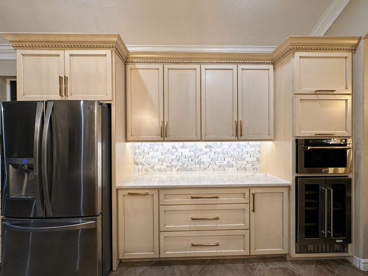 A modern kitchen with cream-colored cabinetry, stainless steel appliances, and a tiled backsplash.