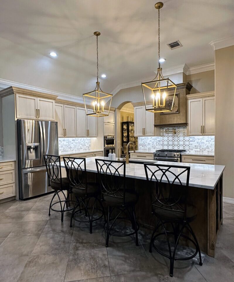 Exceptional custom furnishing in a modern kitchen with white countertops, stainless steel appliances, and pendant lighting over a center island with barstools.