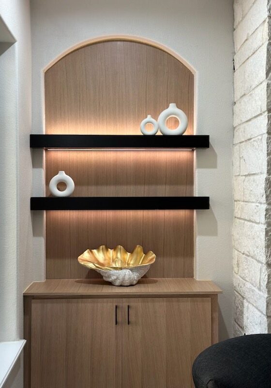 A modern wooden niche with exceptional black shelves, decorative vases, and a golden bowl.