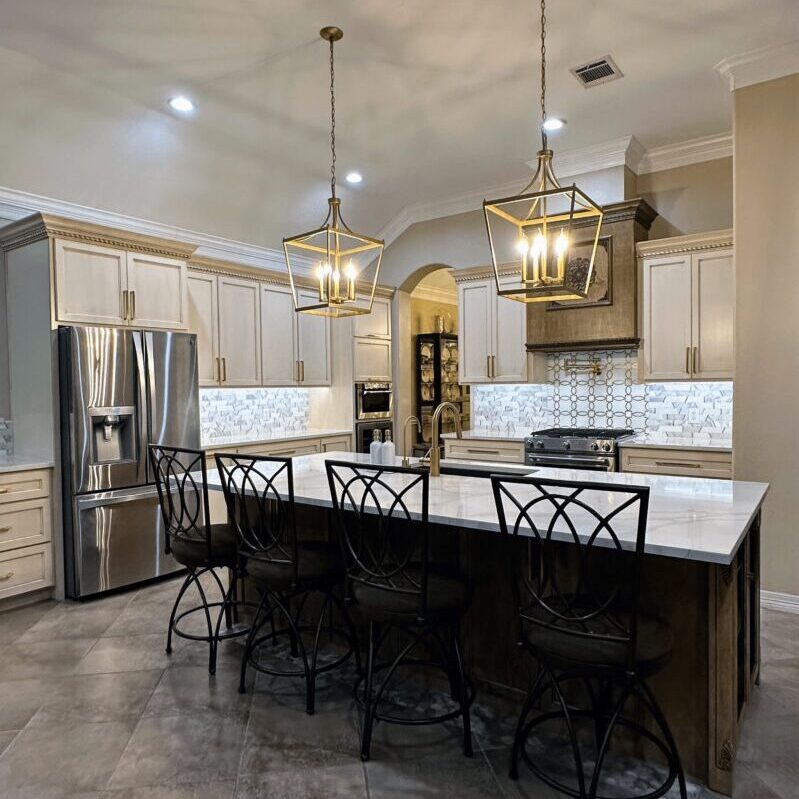Exceptional custom furnishing in a modern kitchen with white countertops, stainless steel appliances, and pendant lighting over a center island with barstools.