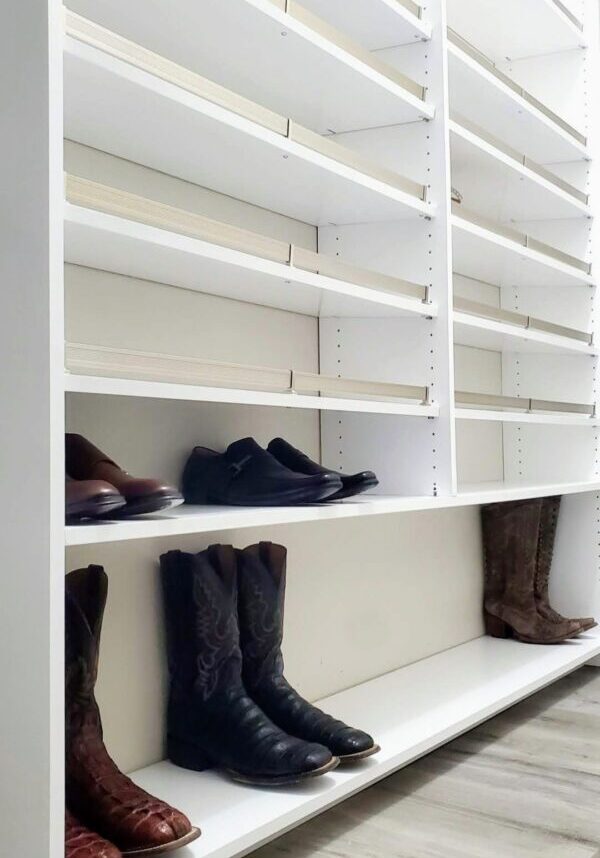        Description: Empty white shelves with a few pairs of exceptional custom-furnished shoes and boots arranged at the bottom.